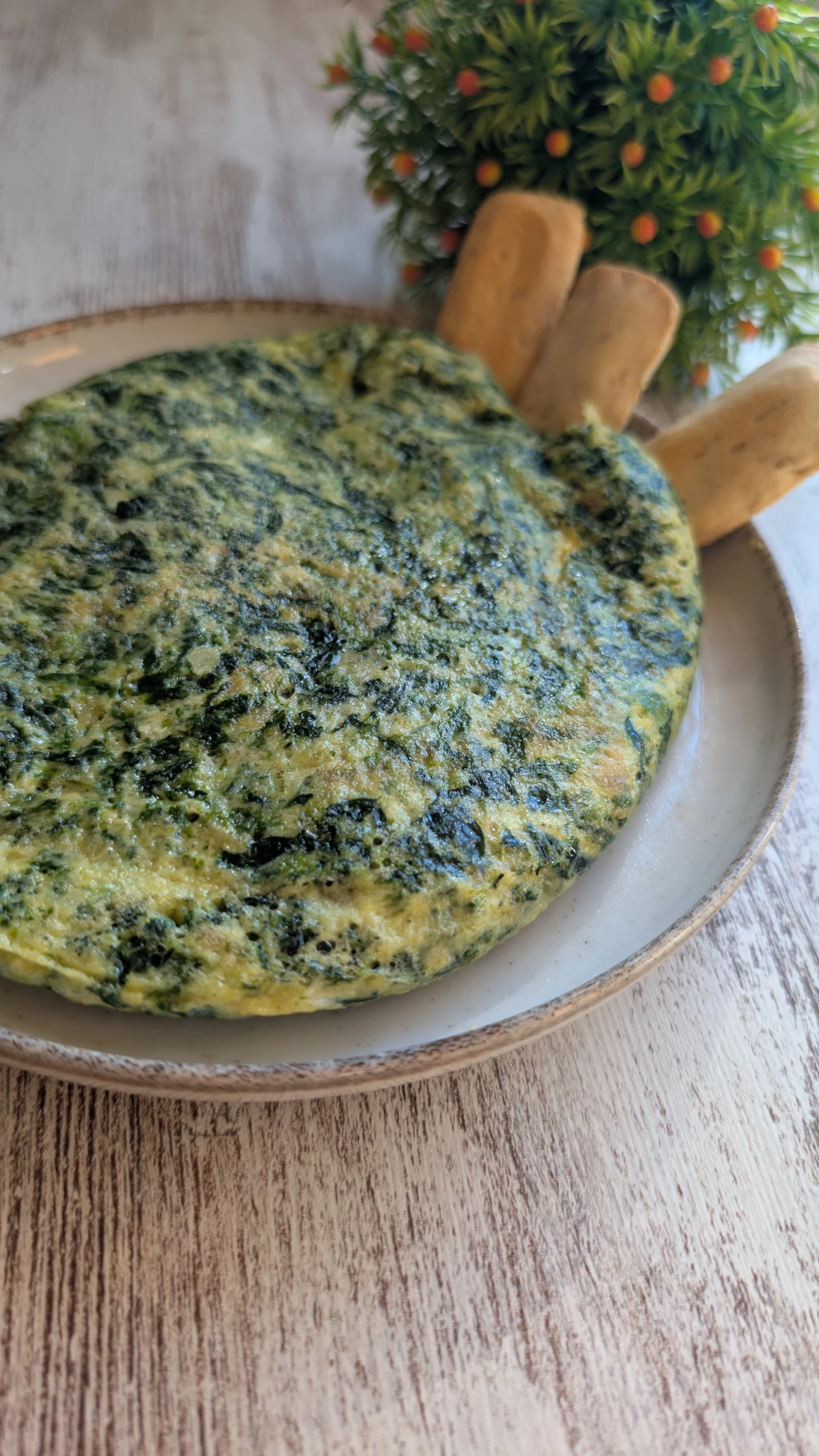 Tortilla de espinacas recién hecha, dorada por fuera y jugosa por dentro, servida en plato blanco.