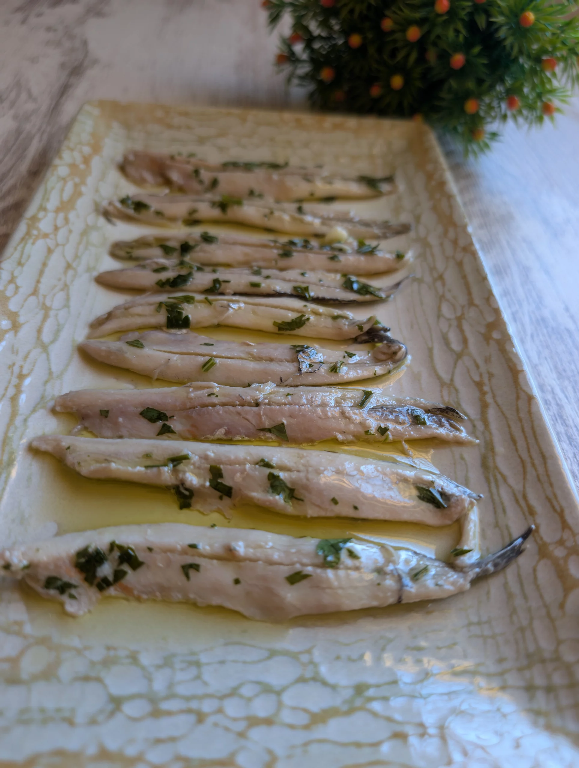 Boquerones en vinagre caseros presentados en un plato con aceite de oliva y perejil
