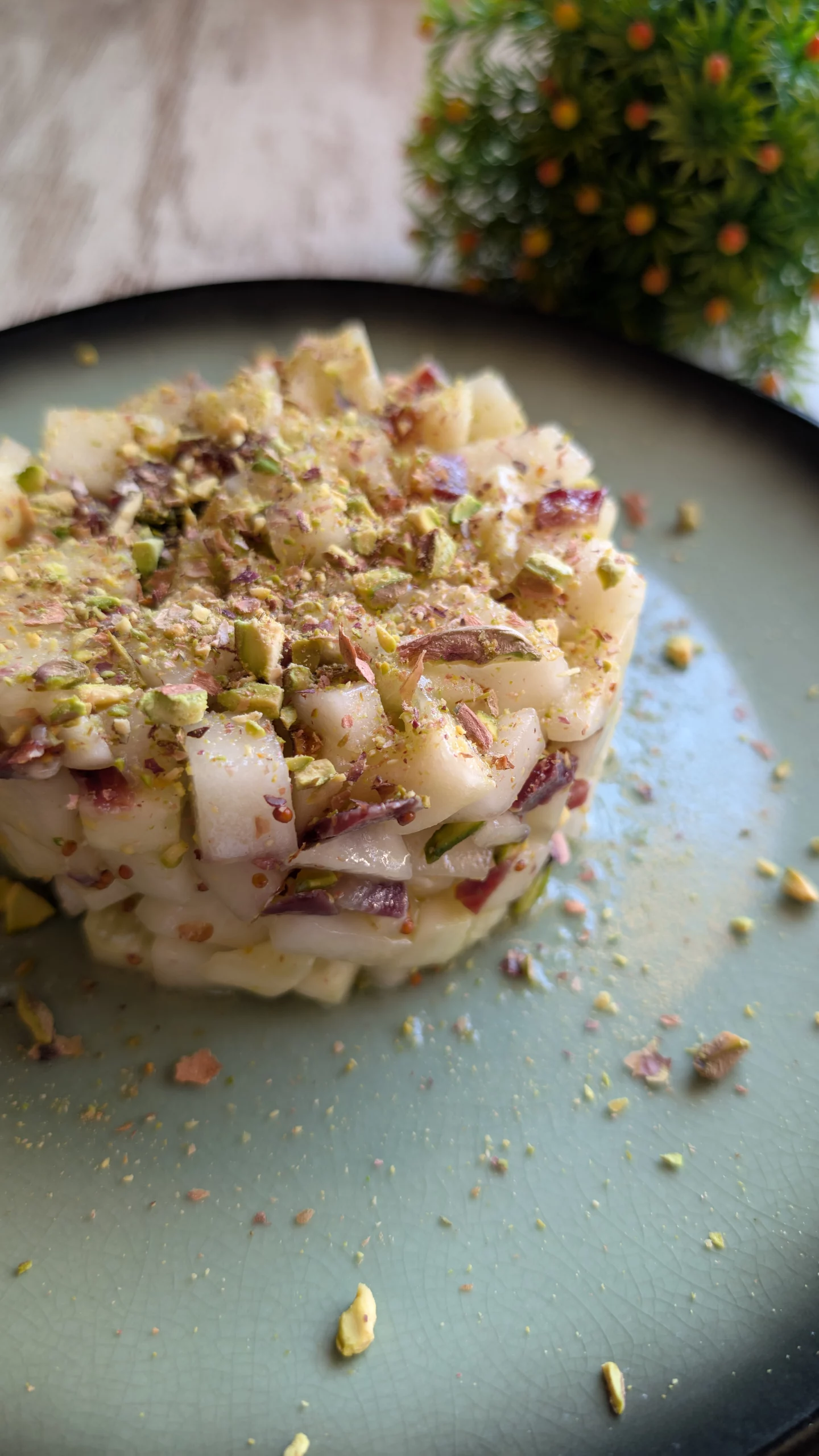 Foto de un tartar de melón y jamón con pistachos machacados, servido en un plato.