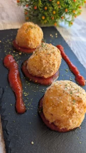 Bombas de patata y zanahoria rellenas de queso, servidas recién hechas, crujientes por fuera y cremosas por dentro.