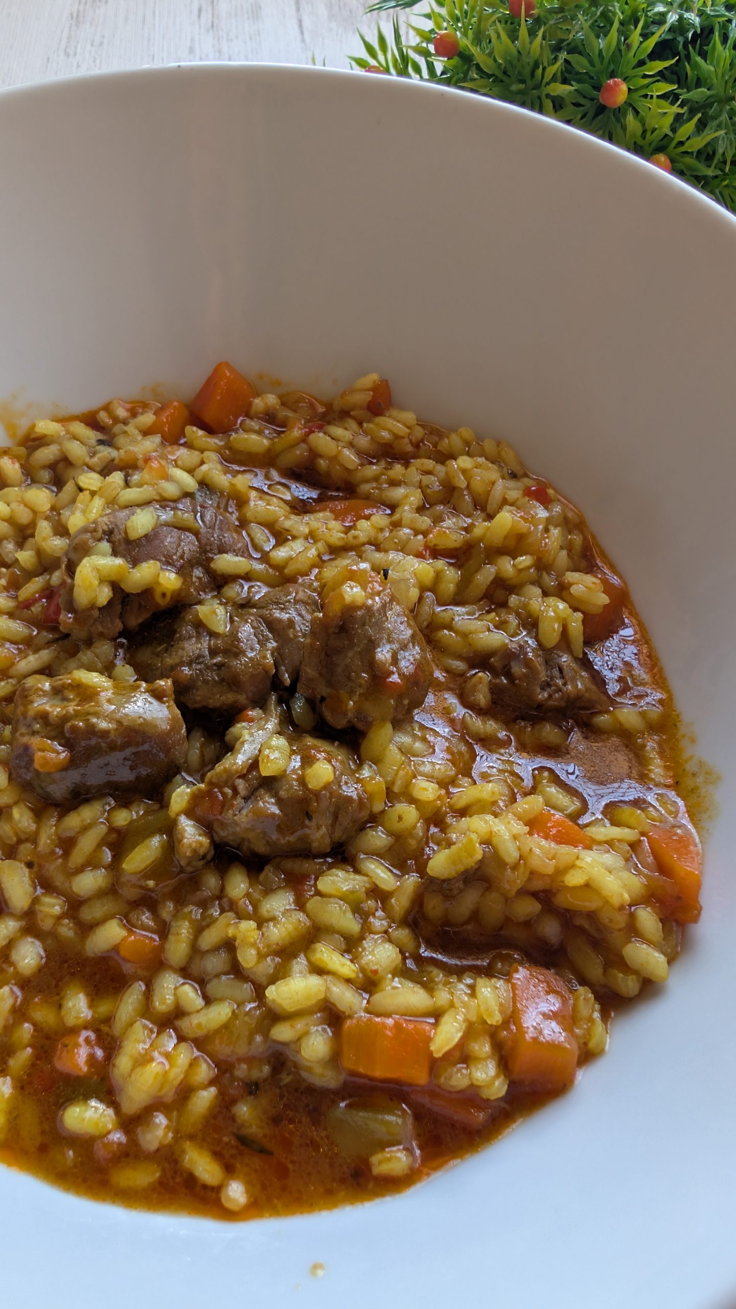 Arroz meloso de carrillada ibérica con trozos de carne, pimiento y zanahoria, con un toque de limón en una cazuela de barro