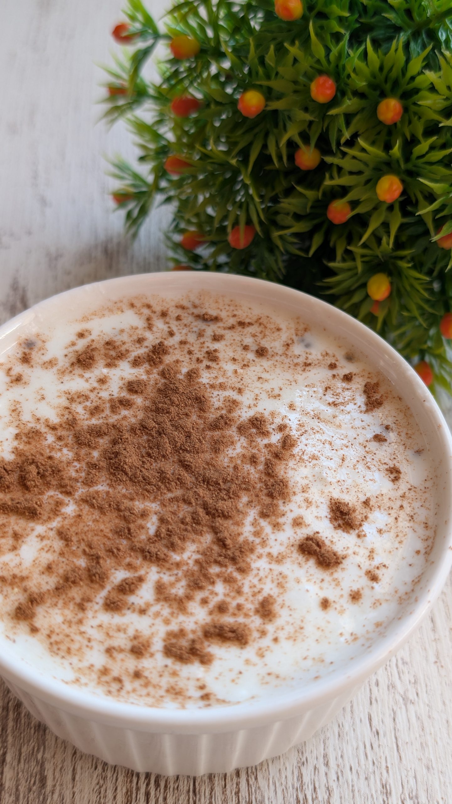 Tarro de avena nocturna (overnight oats) con sabor a arroz con leche, decorado con yogur, canela en polvo y ralladura de limón.