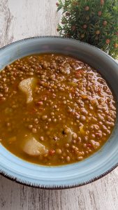 Plato de lentejas rápidas hechas en robot de cocina, con verduras, patata y caldo, listas para comer.