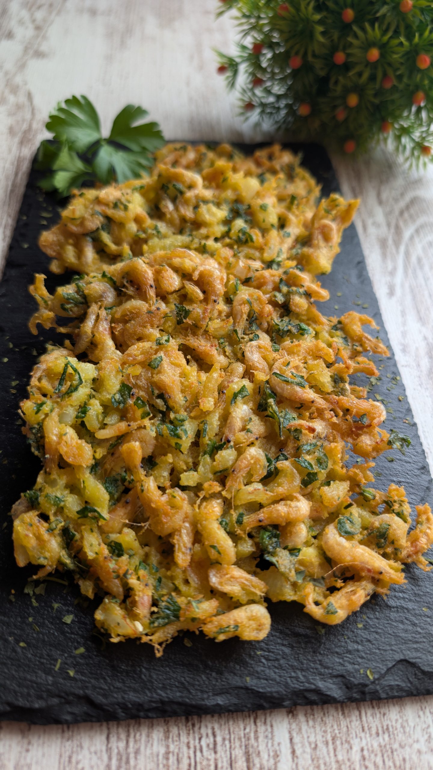 Foto de primer plano de tortillitas de camarones tradicionales, hechas con harina de garbanzo, doradas, crujientes y servidas con perejil picado.
