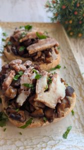 Tosta de pan artesano gratinada con sofrito de setas y pasas al vino Pedro Ximénez, con queso de cabra fundido por encima.