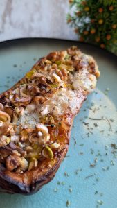 Mitad de calabaza asada rellena y gratinada con queso azul, nueces, puerro y hierbas aromáticas