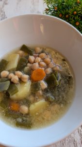 Plato de cocido con garbanzos, carne de gallina, zanahoria y patata, servido en caldo de cocido