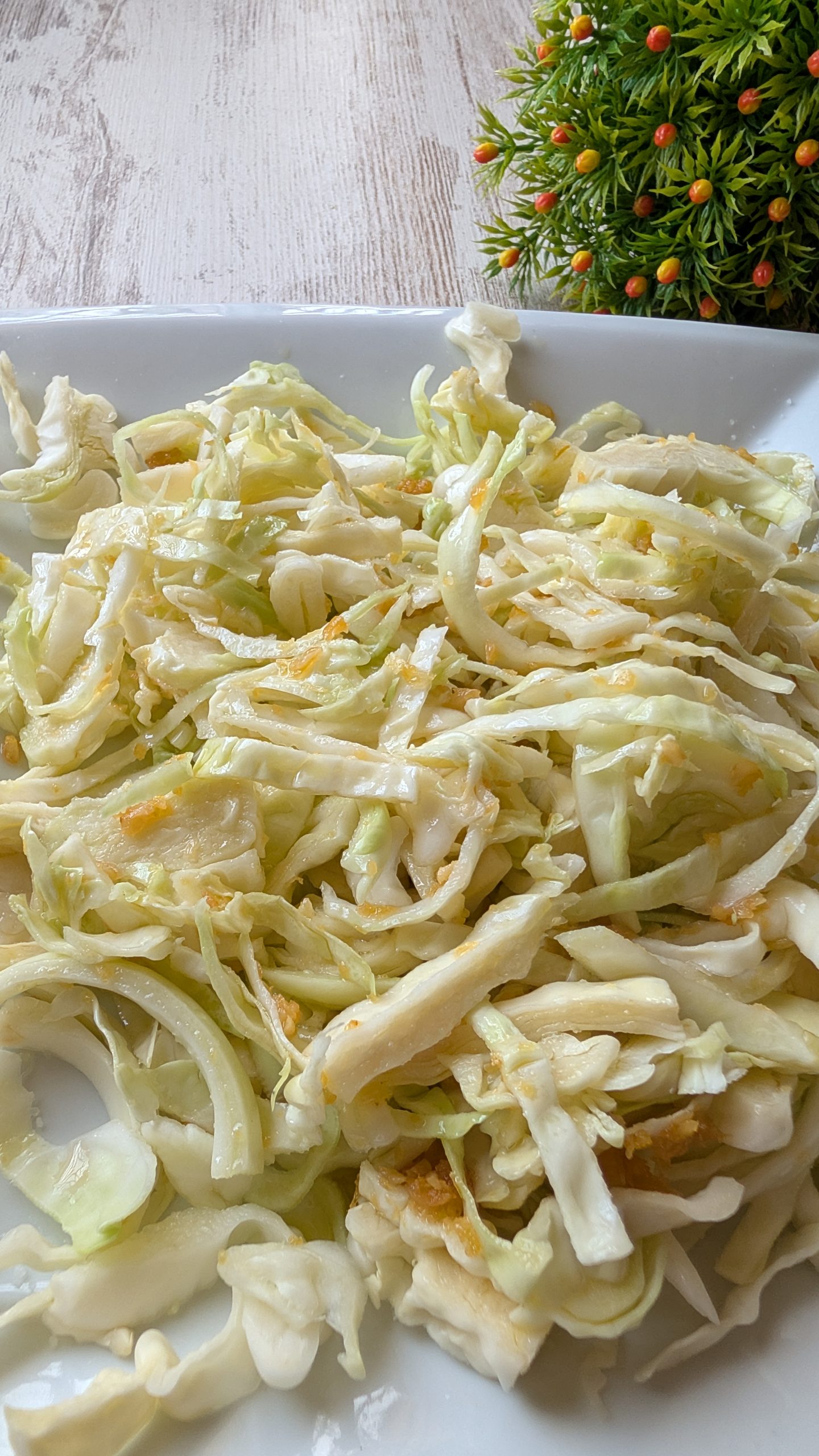 Ensalada de col blanca cortada fina con ajos fritos laminados y aliño de vinagre y aceite de oliva.