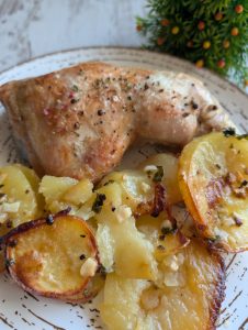 Muslos de pollo asados dorados con patatas y mantequilla, servidos directamente de la fuente de horno