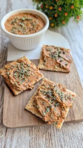 Paté cremoso de tomates secos en AOVE, almendras y orégano, servido en un bol rústico con pan tostado y hojas fresca