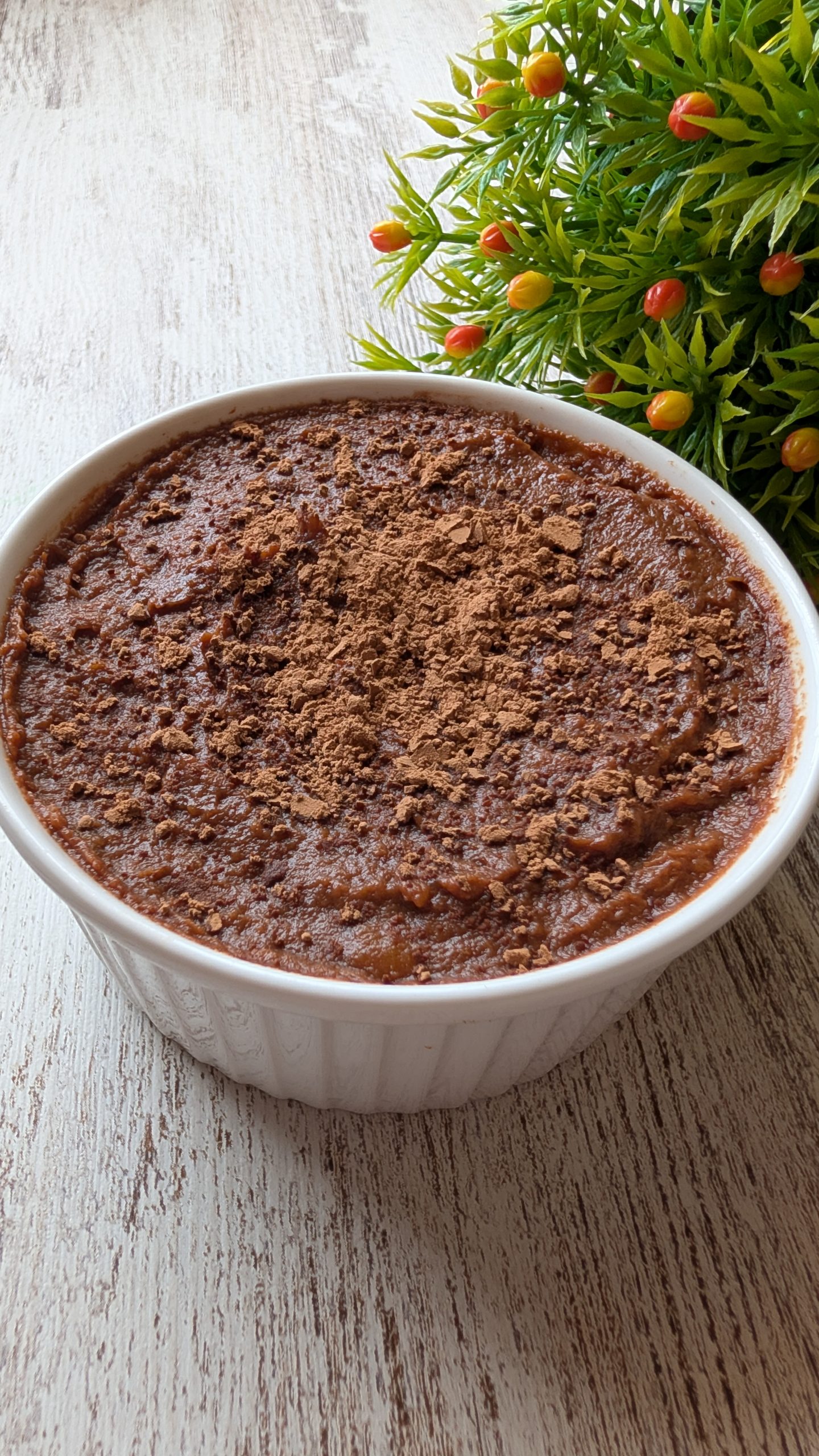 Mousse de boniato y cacao espolvoreado con cacao en polvo en un vaso pequeño. Postre saludable vegano y sin azúcar refinado.