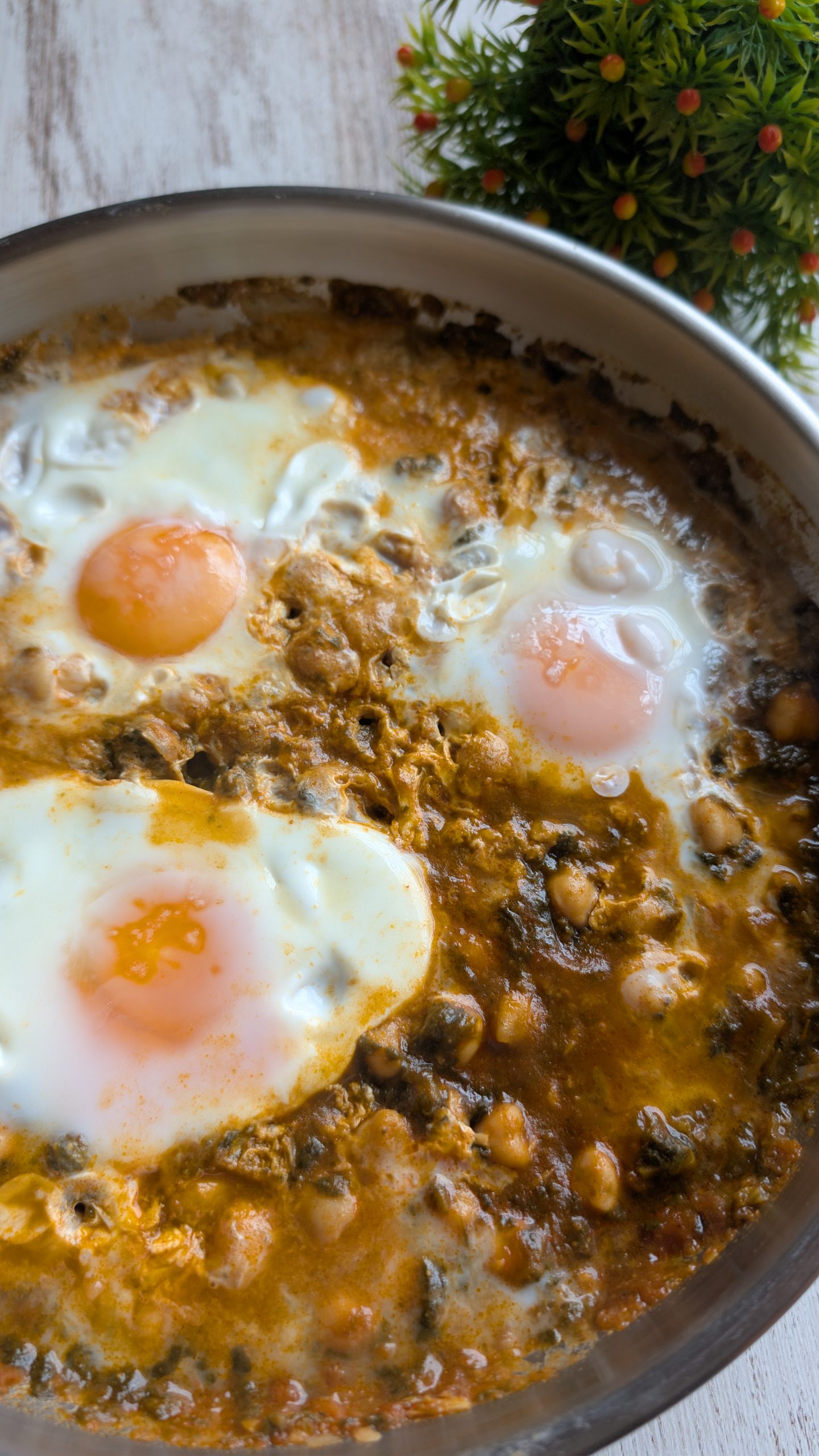 Sartén con garbanzos con espinacas, salsa de tomate y huevos cuajados por encima con ajos fritos.