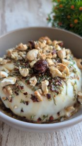 Queso de cabra en rulo fundido en freidora de aire cubierto con miel, nueces troceadas y ají, servido con tostadas.