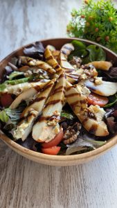 Ensalada de brotes verdes con peras asadas rellenas de queso azul y nueces, aliñada con vinagreta.