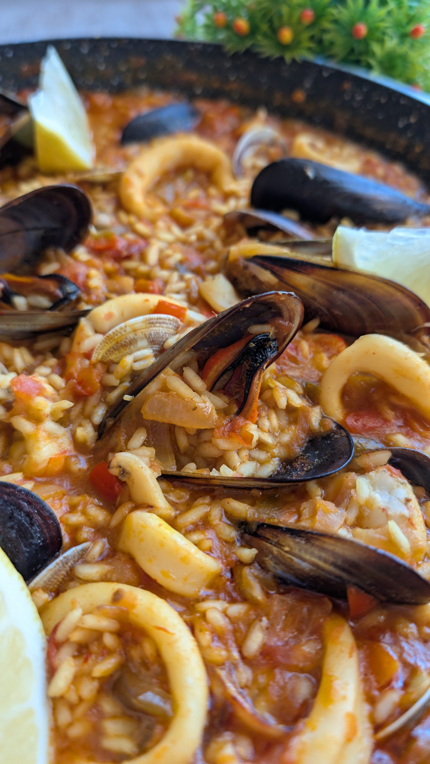 Paella de arroz con marisco decorada con langostinos, mejillones y almejas en una base de sofrito con azafrán.