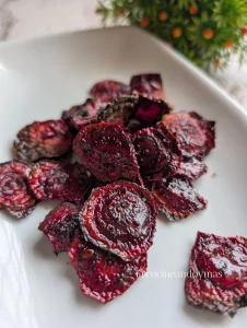 Chips de remolacha crujientes de color púrpura intenso en un cuenco de madera, preparados sin aceite.