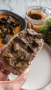 Recipiente con manteca colorá casera de color rojizo por el pimentón, con trozos de carne de cerdo ibérico.