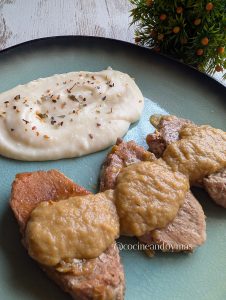 Medallones de solomillo en salsa de whisky y puerro servidos en una fuente con ajos y laurel.