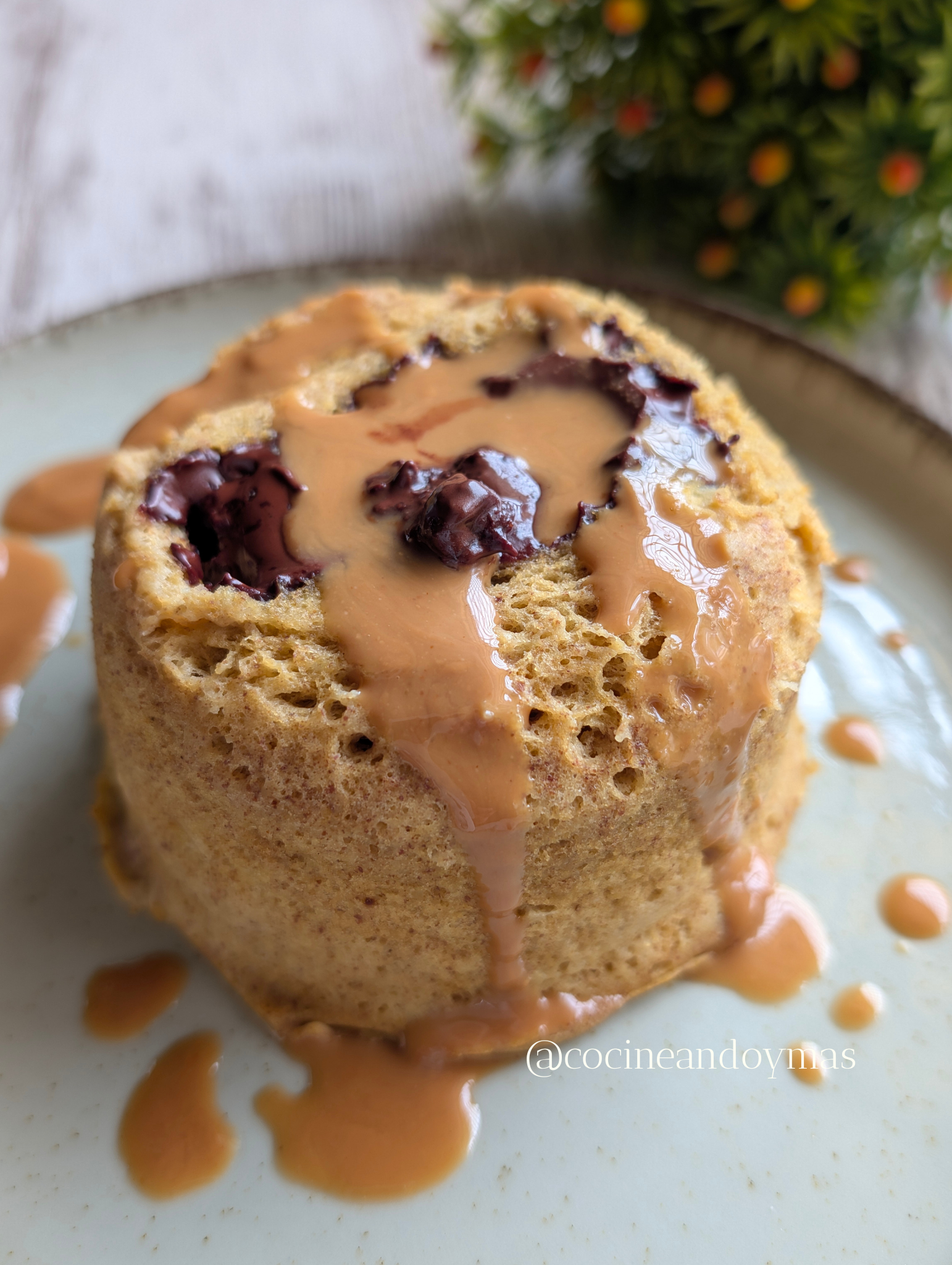 Bizcocho individual en taza (mugcake) de plátano y cacahuete con chocolate fundido saliendo del centro.