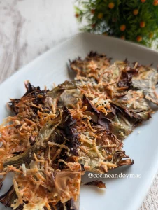 Láminas finas de alcachofa asadas y crujientes con queso fundido por encima en la cesta de una freidora de aire.