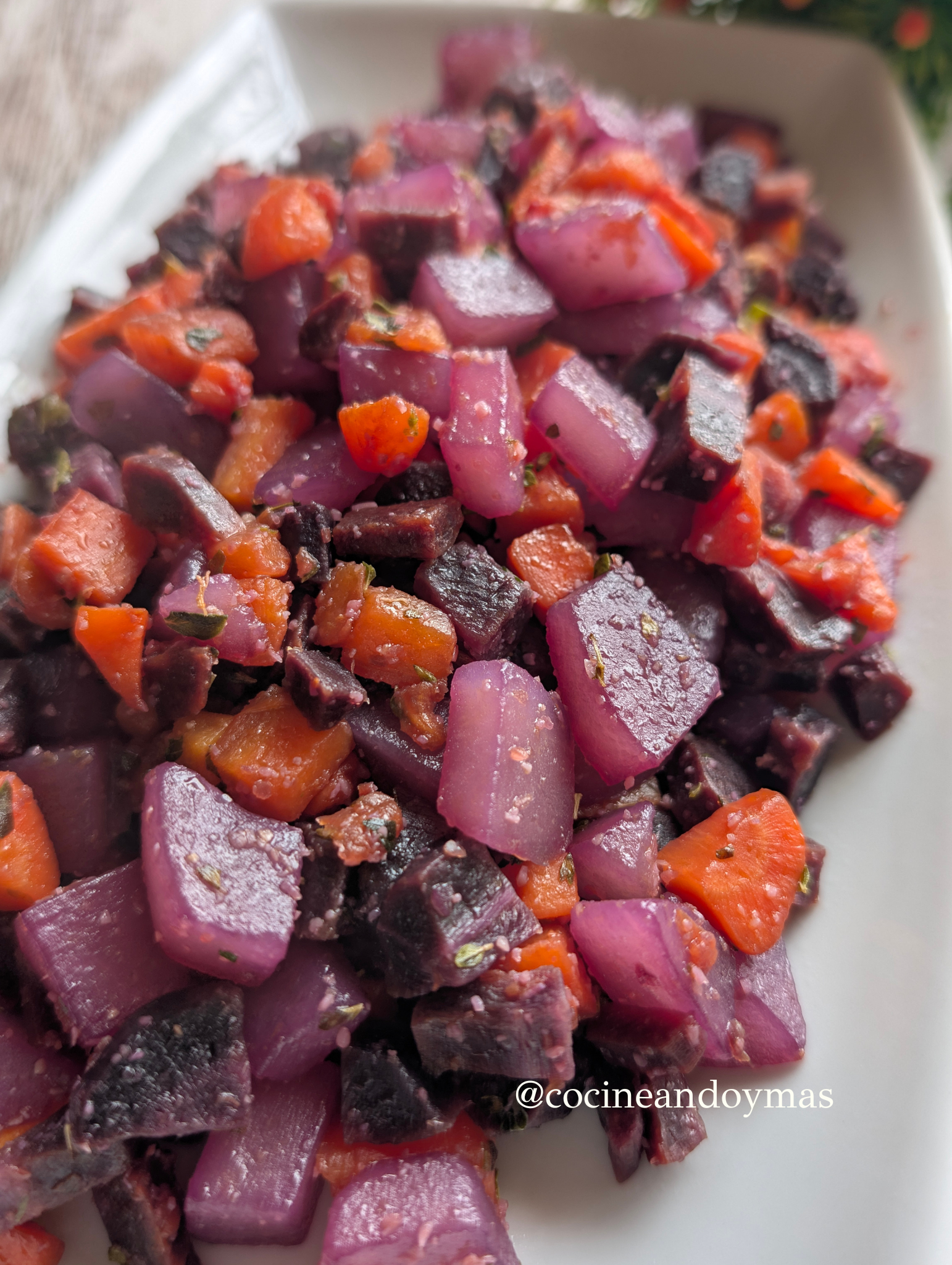 Dados de patata teñidos de morado y zanahorias salteadas con especias en una sartén con aceite de oliva.