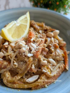 Plato de Pad Thai casero con fideos de avena, pollo, verduras salteadas, huevo y cacahuetes picados por encima.