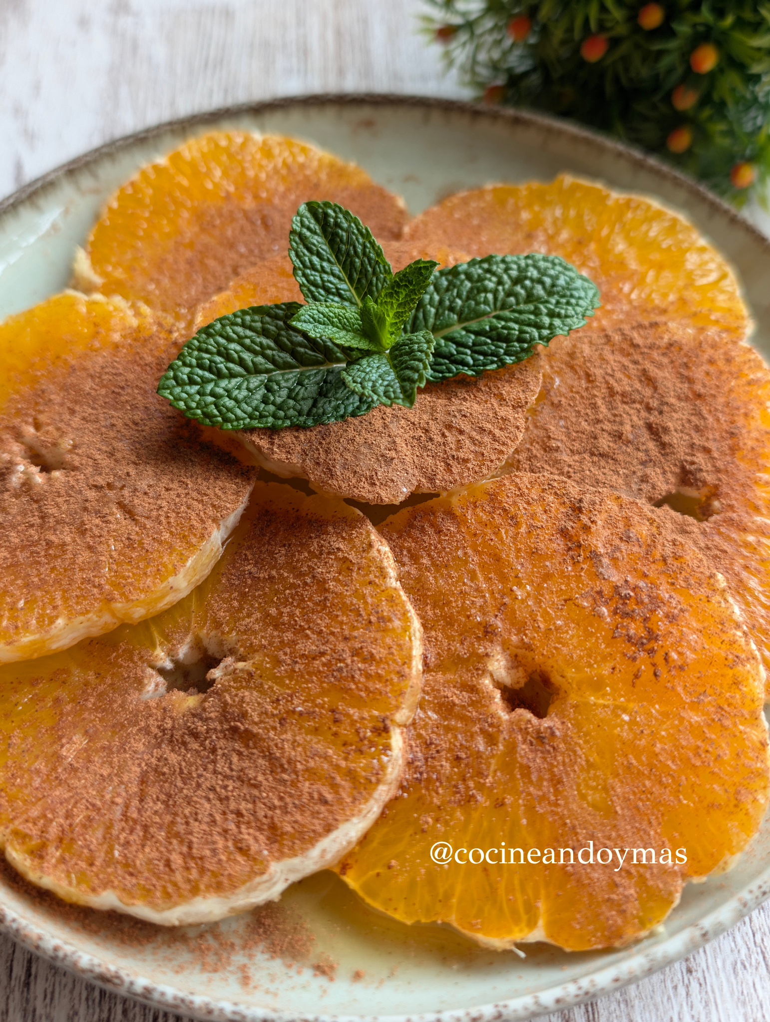 Rodajas de naranja fresca espolvoreadas con canela y un hilo de aceite de oliva sobre un plato de cerámica.