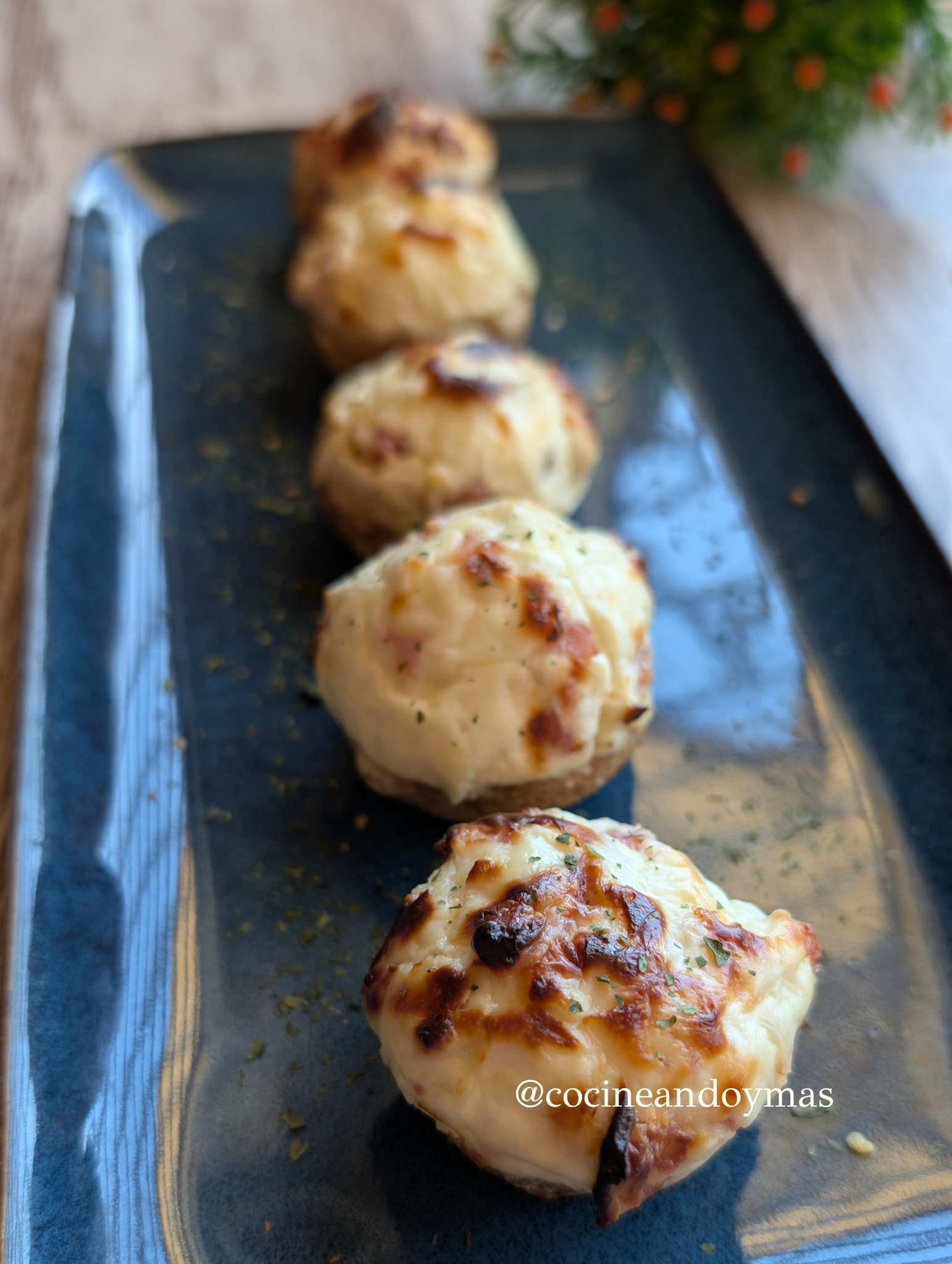 Champiñones grandes rellenos de crema de queso y jamón picado cocinados en freidora de aire, servidos en una bandeja.