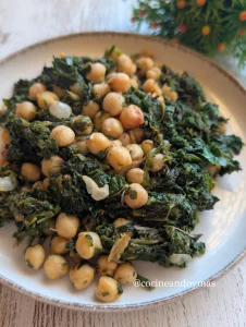 Salteado de garbanzos con espinacas verdes, ajos dorados y un toque de pimentón en una sartén.
