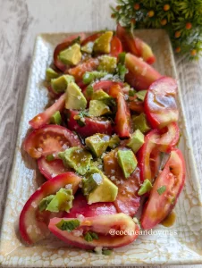 Ensalada fresca de rodajas de tomate y láminas de aguacate con albahaca fresca y vinagreta oscura de Pedro Ximénez.