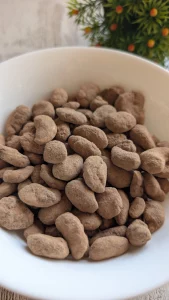 Rocas crujientes de frutos secos cubiertas de chocolate negro 85% y rebozadas en cacao en polvo sobre papel de horno.