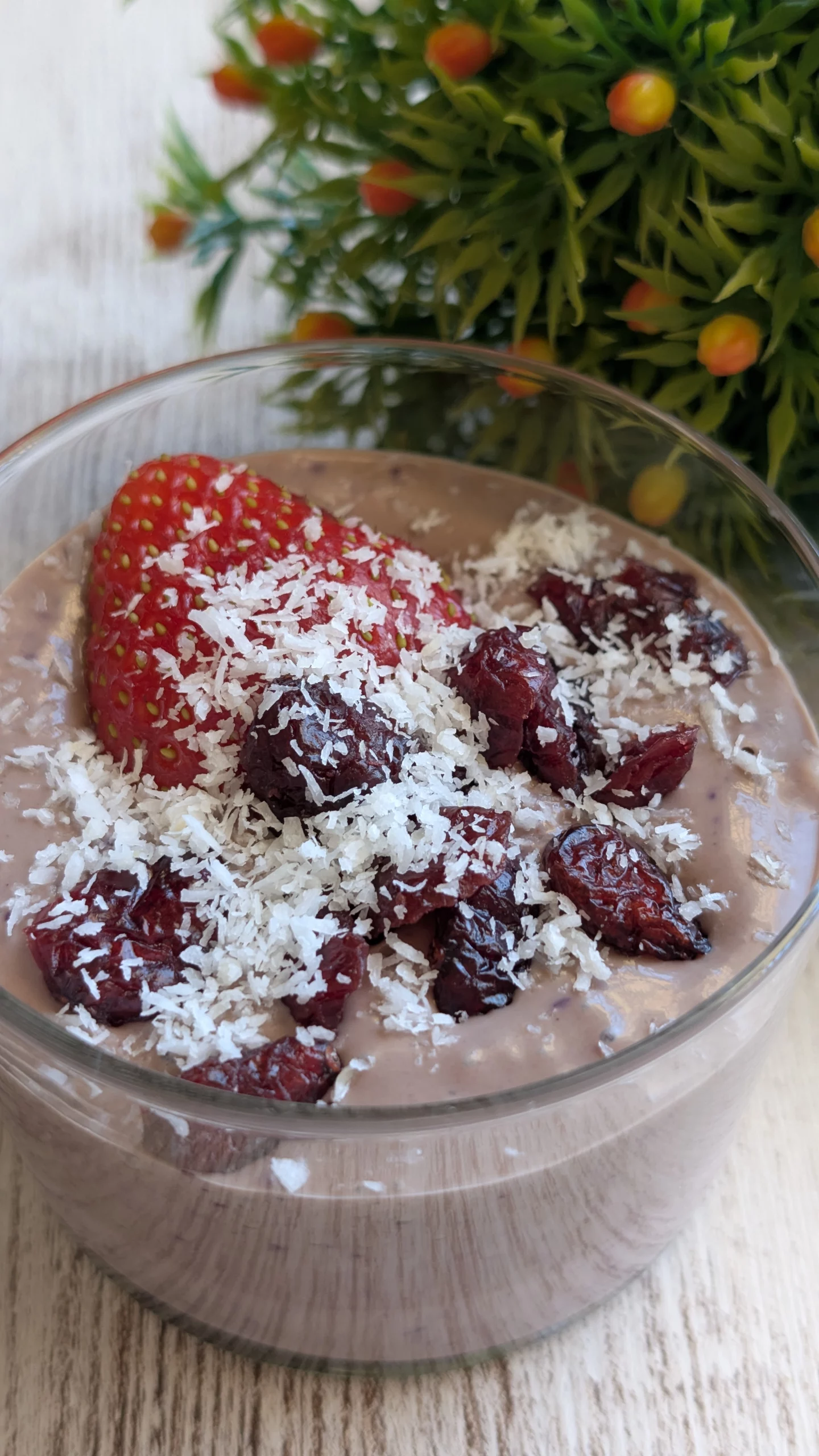 Bowl morado de crema de açaí y queso cottage batido, decorado con fresas, coco rallado, arándanos secos y virutas de chocolate negro.