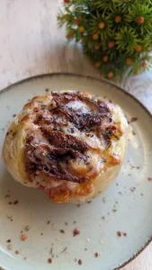 Mitades de patatas asadas y rellenas de pollo, tomates cherry y tomate seco, cubiertas con una capa gruesa de queso gratinado y dorado en airfryer.