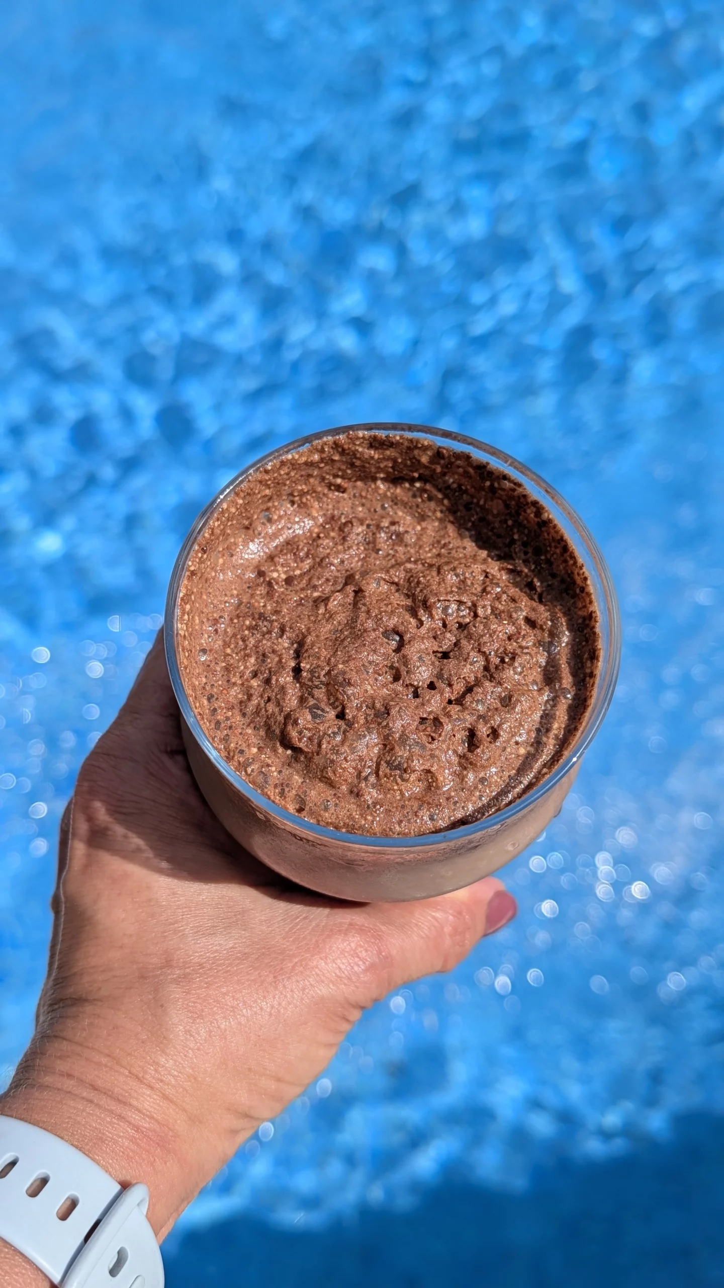 Tres vasos con batidos proteicos espumosos de color chocolate, rosa y beige, decorados con cacao, arándano en polvo y canela respectivamente.
