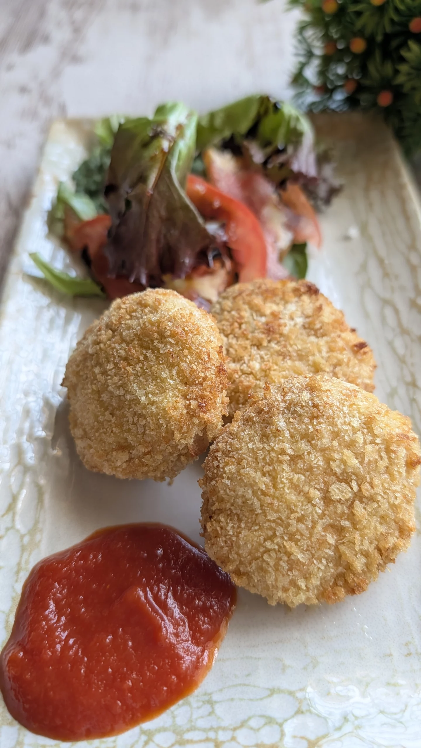 Plato de nuggets de pollo caseros con rebozado de panko dorado y crujiente hecho en airfryer, acompañados de un cuenco pequeño de salsa de tomate natural.