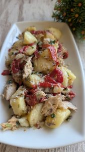 Fuente tradicional con patatas cocidas aliñadas con vinagreta de ajo y perejil, cubiertas con lomos de caballa, tiras de pimiento del piquillo y escamas de sal.