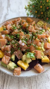 Tartar montado en aro con base de láminas de remolacha, capas de aguacate, mango y salmón picado con sésamo y cebollino.
