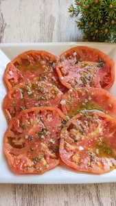Fuente tradicional con rodajas de tomate maduro aliñadas con aceite de oliva virgen extra, vinagre, orégano, comino y flor de sal.