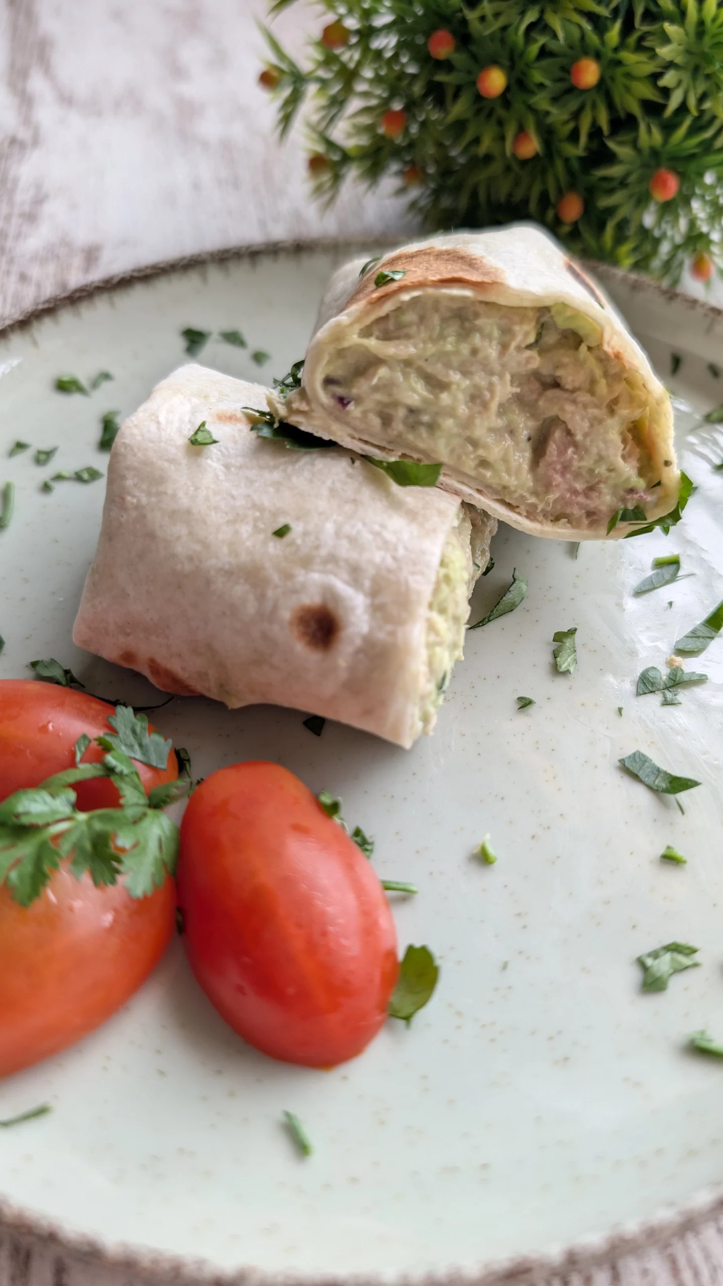 Wrap de tortilla integral relleno de pasta cremosa de atún, aguacate, cebolla morada y cilantro, cortado por la mitad.