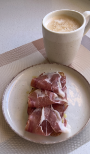 Rebanada de pan artesanal tostado regada con aceite de oliva virgen extra, cubierta con rodajas de tomate fresco y lonchas de jamón ibérico.