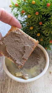 Tarro de cristal con paté casero de hígado cremoso, sellado con mantequilla y acompañado de rebanadas de pan tostado.