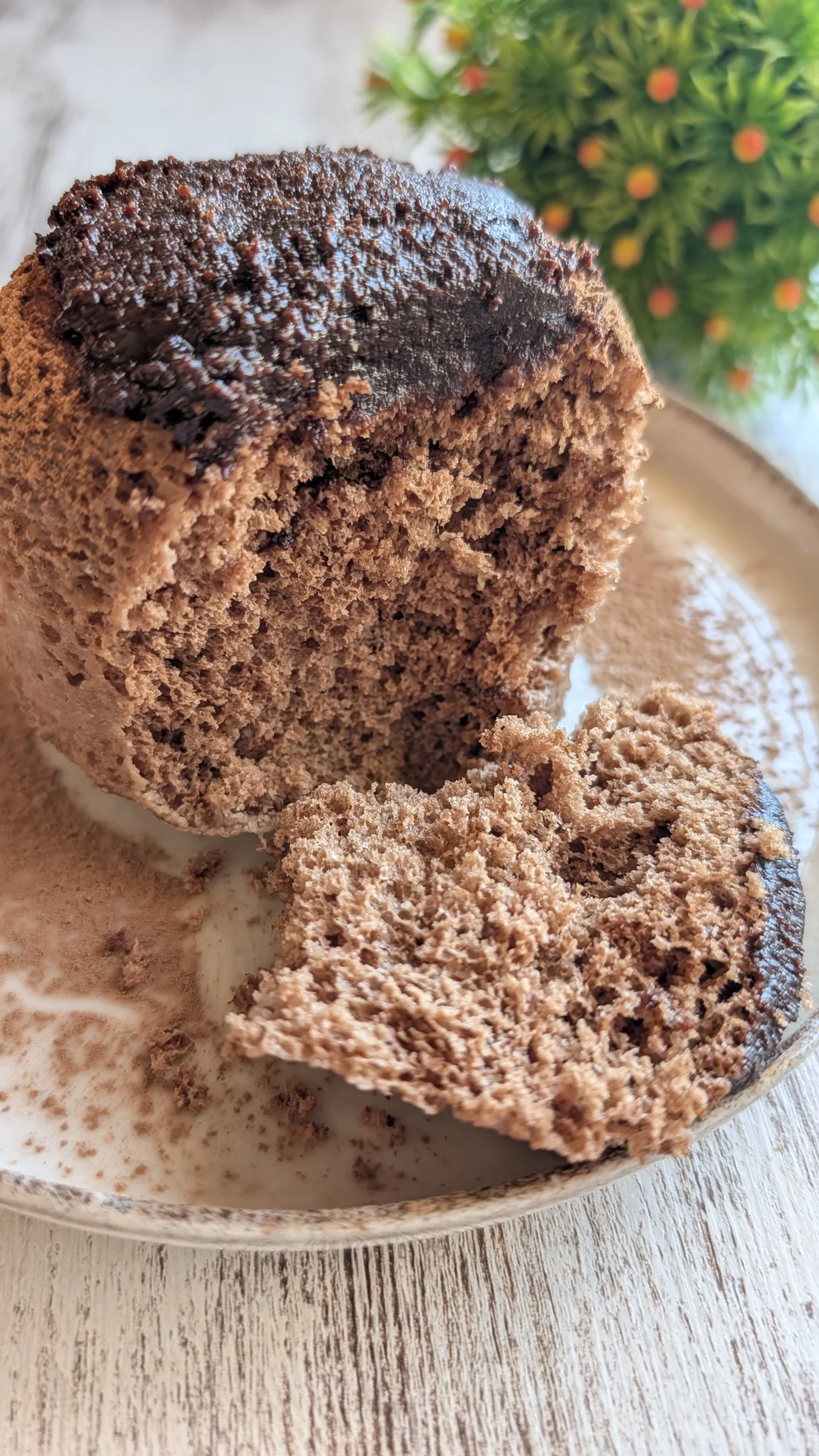 Bizcocho proteico en taza recién hecho al microondas, con cacao en polvo y crema de frutos secos por encima.